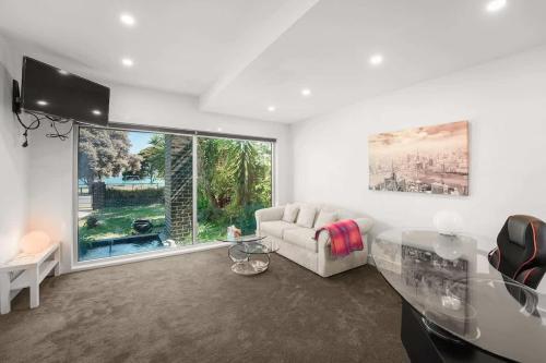 a living room with a couch and a large window at Water Front at Geelong Holiday K Villa in North Shore