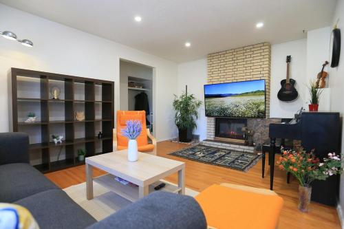 ein Wohnzimmer mit Sofa und Fernseher in der Unterkunft Rocky Mtn Escape-3 bdrm-near shops, dining, UofC in Calgary