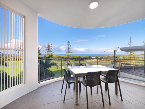a dining room with a table and chairs and a large window at Meridian Alex Beach Apartments in Alexandra Headland