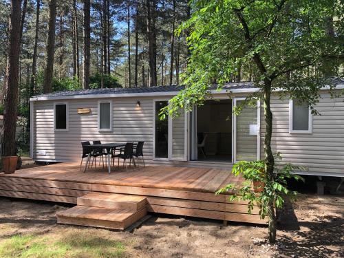 a cabin with a wooden deck with a table and chairs at Tiny house in the Antwerp Kempen in Beulk
