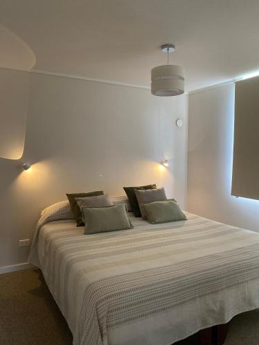 a bedroom with a large white bed with two pillows at Departamento cálido y espacioso con estacionamiento privado in Valdivia