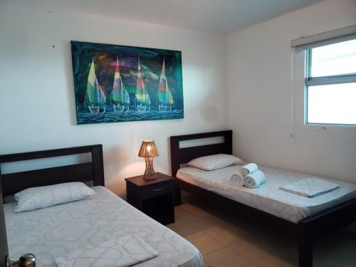 a bedroom with two beds and a lamp on a table at Departamento con piscina 8 in Salinas