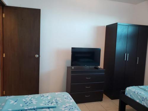 a bedroom with a tv and a dresser with a bed at Departamento con piscina 8 in Salinas