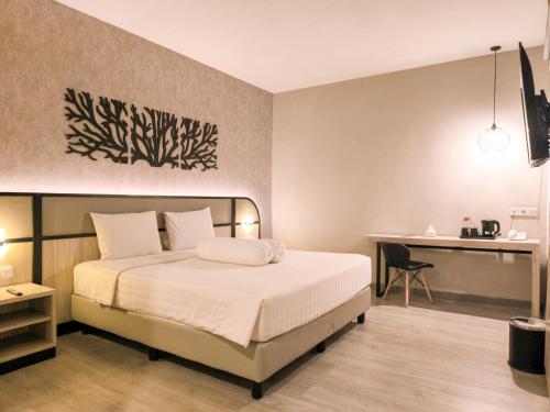a bedroom with a bed and a desk at Front One Gosyen Hotel Salatiga in Salatiga