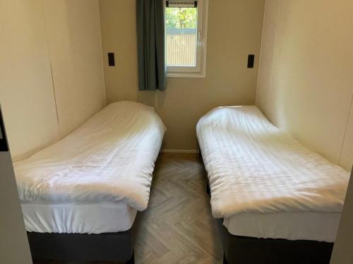 two beds in a small room with a window at Chalet in Beekbergen near Veluwe Forest in Beekbergen