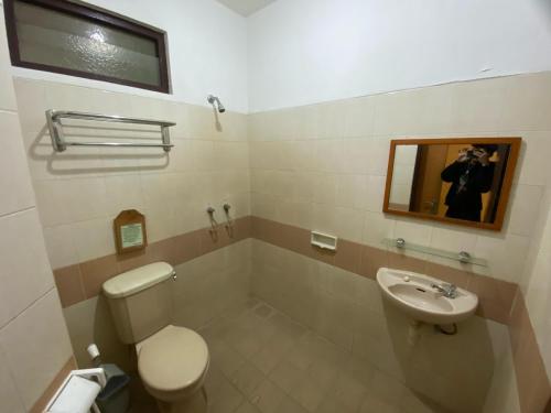 a bathroom with a toilet and a sink and a mirror at Lestari Hotel & Resto in Berpodak