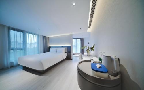 a bedroom with a bed and a desk with a tv at Atour Light Hotel Shenzhen Nanshan Nanyou Clothing City in Shenzhen