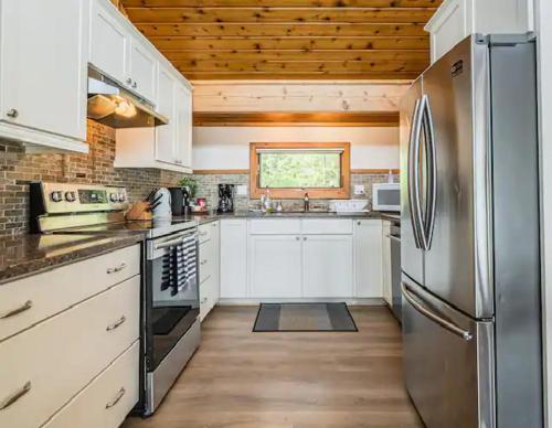 Una cocina con gabinetes blancos y un refrigerador de acero inoxidable. en Cobblestone Waterfront cottage 4 Bedrooms, 2 Bathrooms, Sauna at Lion Head, en Lions Head