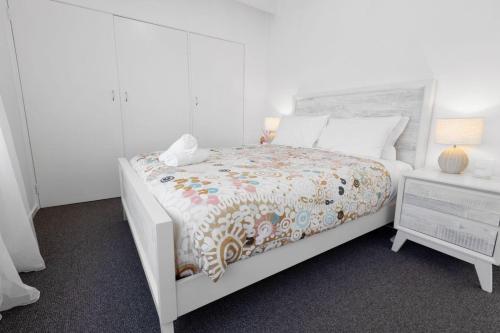 a white bedroom with a bed and a night stand at Serenity in Lakes Entrance