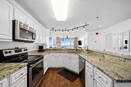 a kitchen with white cabinets and granite counter tops at Pool & Spa - Beachfront - Golf - King Bed in Gulf Highlands