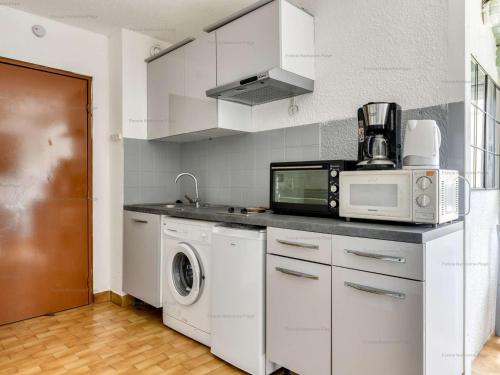 une cuisine avec un micro-ondes et un lave-linge et un sèche-linge dans l'établissement Studio 4 pers, plage à 200m, parking, Narbonne Plage - FR-1-229B-105, à Narbonne
