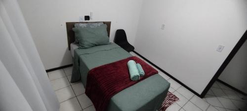 a small bedroom with a bed with a phone on it at Quarto em casa de família in Joinville