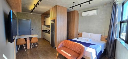 a bedroom with a bed and a desk and a kitchen at City Zen Studios in Sao Jose do Rio Preto