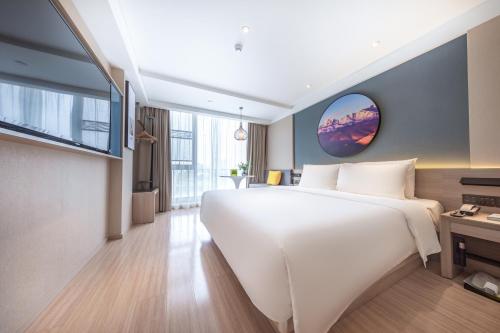 a bedroom with a large white bed and a tv at Atour Light Hotel (Chengdu Hi-tech West Zone University of Electronic Technology) in Chengdu
