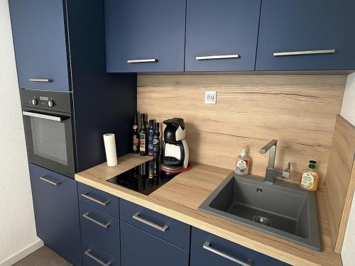 Il comprend une cuisine équipée d'un évier, d'une cuisinière et de placards bleus. dans l'établissement Charmant T2 climatisé rénové, proche plage et commerces à Argelès-sur-Mer, avec balcon et parking privé - FR-1-732-68, à Argelès-sur-Mer