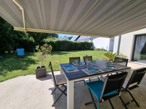 une table à manger sous un auvent dans une cour arrière dans l'établissement Maison au calme avec jardin, 3 chambres, plage et commerces à proximité, WiFi, animaux acceptés - FR-1-775-20, à Sarzeau