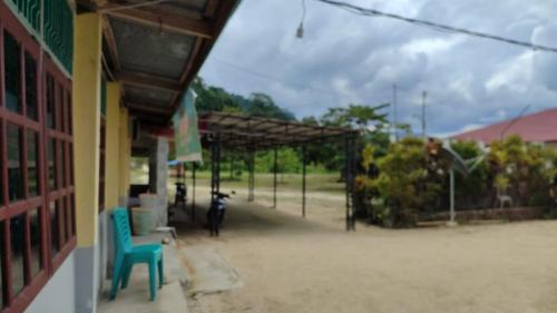 a building with two blue chairs sitting outside of it at Viunya Gaga Homestay in Mantang