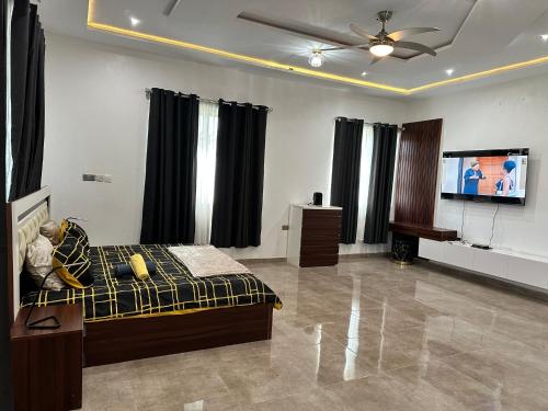 a living room with a bed and a flat screen tv at Nanani Luxury Villa in Kumasi