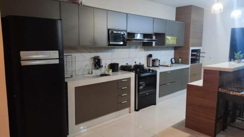 a kitchen with a black refrigerator and a stove at Casa espaçosa, toda climatizada, com piscina, área gourmet, playground in Cuiabá