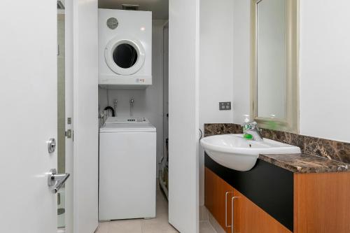 a bathroom with a sink and a washing machine at Fabulous Corner Apartment w/ Dazzling Harbour View in Auckland