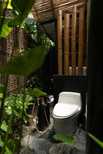 a toilet in a garden with a fence at Sanctuary Kanchanaburi in Ban Ai Hit