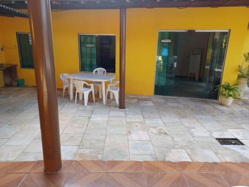 a patio with a table and chairs and a yellow wall at Cantinho da paz in Maragogi