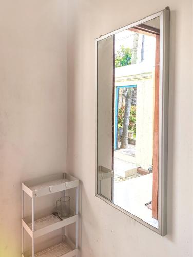 a mirror on a wall next to a shelf at Palma Family Hall Klaten in Kuwoso