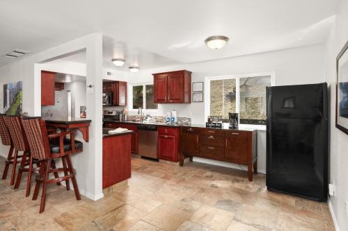 a kitchen with wooden cabinets and a black refrigerator at Rivertop Hideaway with HUGE views-Hot Tub-EV-more! in Ahwahnee