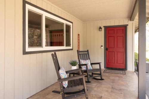 a porch with two chairs and a red door at Rivertop Hideaway with HUGE views-Hot Tub-EV-more! in Ahwahnee