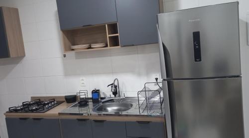 a kitchen with a stainless steel refrigerator and a sink at Apartamento do Viajante Econômico in Jaraguá do Sul