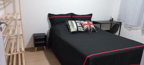 a bedroom with a bed with black sheets and pillows at Apartamento do Viajante Econômico in Jaraguá do Sul
