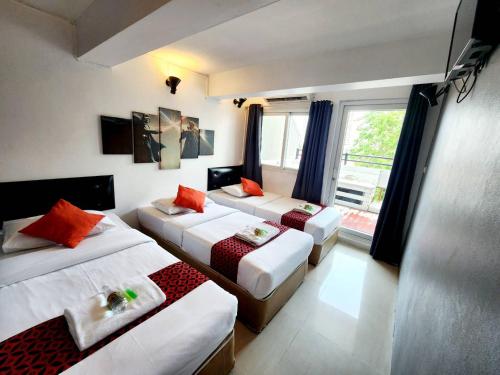 a hotel room with three beds and a window at Khaosan Art Hotel in Bangkok