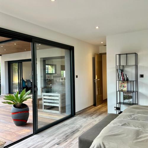 une chambre avec des portes vitrées et une plante en pot dans l'établissement Villa Miroir d'O - Piscine chauffée, à Gujan-Mestras