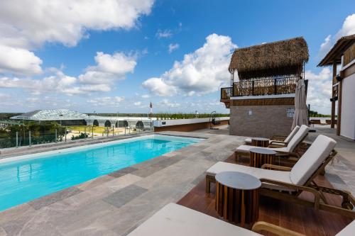 a swimming pool with lounge chairs and a building at Hotel Mundo Maya Tulum Aeropuerto in Tulum