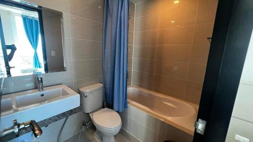 a bathroom with a toilet and a sink and a tub at Mactan Newtown Beach Condo in Lapu Lapu City