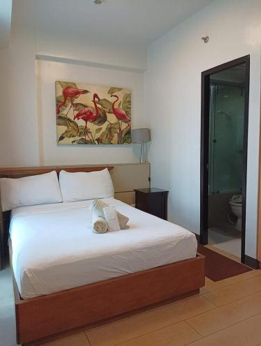a bedroom with a bed and a picture of birds at Mactan Newtown Beach Condo in Lapu Lapu City