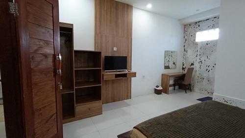 a bedroom with a bed and a desk with a television at Brown Homestay in Kuta Lombok