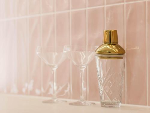 a bottle with a gold top next to three wine glasses at Upper Lvl Boyd-3 Bedroom Sunny Coastal in Tweed Heads