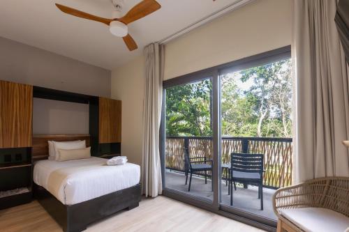 a bedroom with a bed and a balcony at Hotel Mundo Maya Tulum Aeropuerto in Tulum
