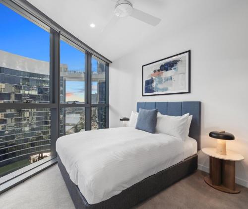 a bedroom with a large bed and a large window at Queen's Wharf Residences Official in Brisbane