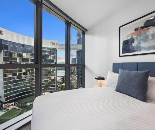 a bedroom with a white bed and large windows at Queen's Wharf Residences Official in Brisbane