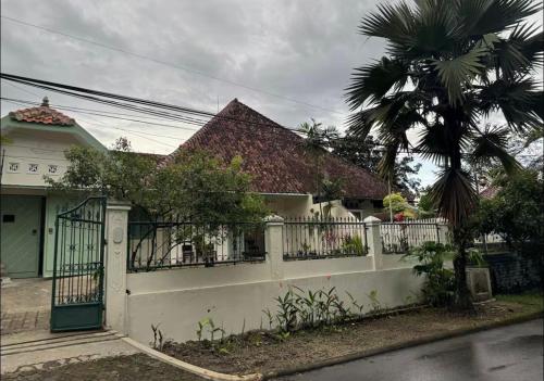 a house with a white fence and a palm tree at vintage room 1 in colonial house in Kamparganya