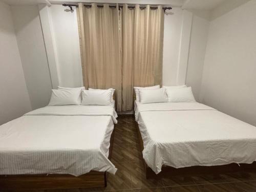 two beds in a small room with white sheets at Kundasang Guesthouse in Kundasang