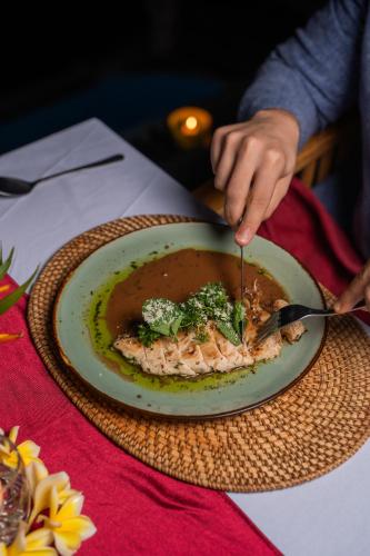 a person eating a plate of food with a fork and knife at Abasan Hill Hotel and Spa in Nusa Penida
