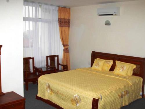 a bedroom with a bed and two chairs and a window at Bank Star Hotel in Ðố Sơn
