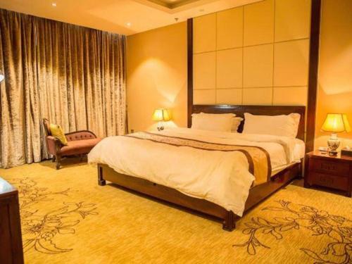 a hotel room with a large bed and a chair at Erdos Great Gate Hotel in Hantai