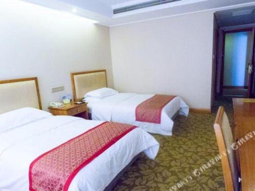 a hotel room with two beds and a window at Jincheng Pacific Hotel in Jincheng