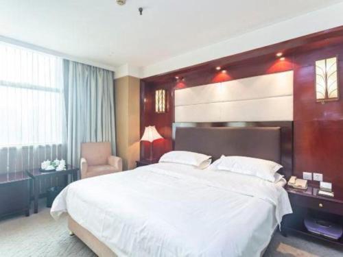 a bedroom with a large white bed and a chair at Jincheng Pacific Hotel in Jincheng