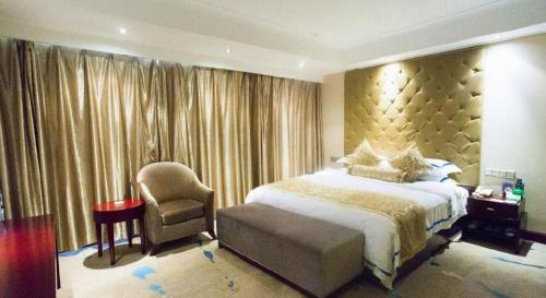 a bedroom with a large bed and a chair at Jincheng Pacific Hotel in Jincheng
