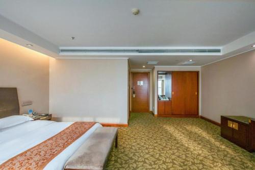 a hotel room with a large bed and a hallway at Jincheng Pacific Hotel in Jincheng